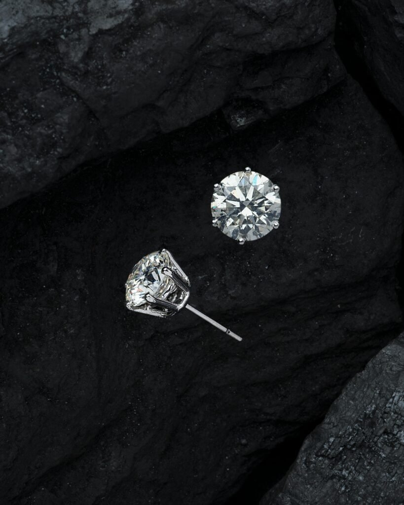 Close-up of luxury diamond earrings on textured black stone, showcasing elegance.